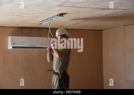 2120th Engineer Company is a unit of the Oklahoma Army National Guard assigned to the 458th Engineer Battalion and 35th Engineer Brigade, operating under Task Force Spartan during Operation Spartan Shield in Iraq. The archival image documents a soldier conducting electrical preparation work prior to installing lighting in an office building as part of an engineer construction project. Stock Photo