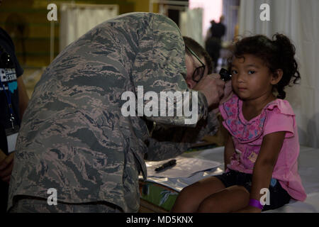 180321-A-YI894-0060 PUERTO CORTES, Honduras (March 21, 2018) An Airman checks Honduran girl ears at during Continuing Promise 2018. U.S. Naval Forces Southern Command/U.S. 4th Fleet has deployed a force to execute Continuing Promise to conduct civil-military operations including humanitarian assistance, training engagements, and medical, dental, and veterinary support in an effort to show U.S. support and commitment to Central and South America. (U.S. Army photo by Spc. Brandon Best/ Released) Stock Photo