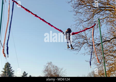 Young girl playing on the bungee trampoline outdoors in a park, Sofia, Bulgaria Stock Photo