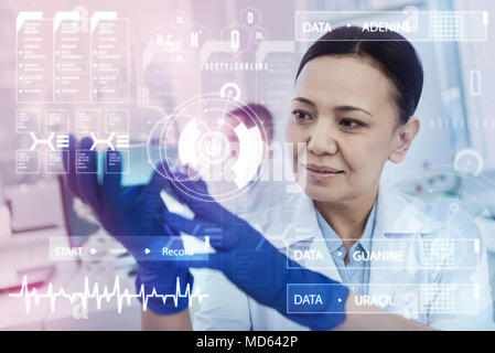 Clever scientist holding a bottle with blue liquid and looking happy Stock Photo