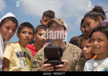 180321-A-YI894-0208 PUERTO CORTES, Honduras (March 21, 2018) Staff Sgt. Daniel Luksan, of Daytona Beach, Florida, flies drone as Honduran kids watches during Continuing Promise 2018. U.S. Naval Forces Southern Command/U.S. 4th Fleet has deployed a force to execute Continuing Promise to conduct civil-military operations including humanitarian assistance, training engagements, and medical, dental, and veterinary support in an effort to show U.S. support and commitment to Central and South America. (U.S. Army photo by Spc. Brandon Best/ Released) Stock Photo