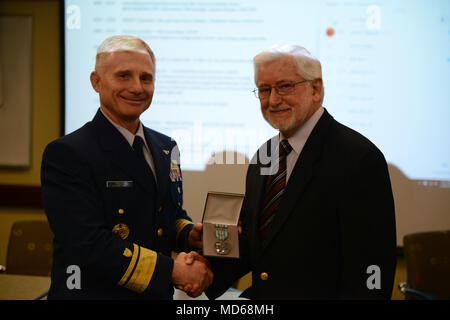 Coast Guard Rear Admiral David Throop, commander, 13th District, presents Alan Allen the Coast Guard’s Meritorious Public Service Award medal, during a meeting of the Northwest Area Contingency Plan committee meeting in Tacoma, Wash., March 28, 2018.    Allen was honored for his efforts and expertise in response to maritime environmental incidents, including having operational oversight of 376 significant in situ oil pollution burns eliminating an estimated 12.6 million gallons of oil, or 17 percent of the total estimated spilled.    U.S. Coast Guard photo by Chief Petty Officer David Mosley Stock Photo