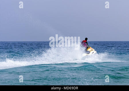 Summer entertainment at the sea. Tourists riding a jet ski. Sea time. summer holidays at the seaside resort. Young guy cruising on the atlantic ocean  Stock Photo