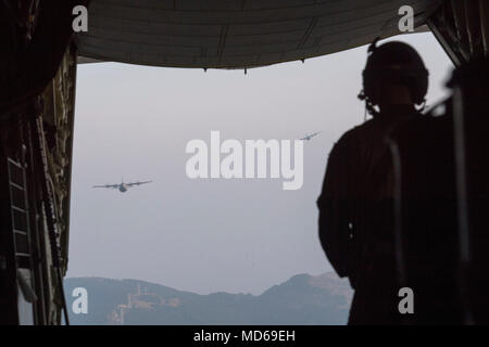 Airman 1st Class Matthew Pfeffer, 36th Airlift Squadron C-130J loadmaster, observes two Air Force C-130J Super Hercules’ over the Combined Arms Training Center Camp Fuji, Japan, March 26, 2018. Crewmembers with the 36th AS conducted airdropping a Container Delivery System (CDS) bundle and heavy equipment pallets to prepare for U.S. Air Force peacetime and contingency operations. (U.S. Air Force photo by Yasuo Osakabe) Stock Photo