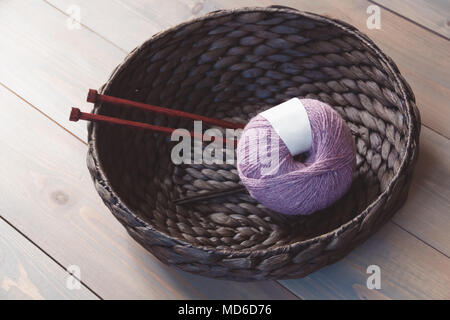 Wool yarn and knitting needles in the basket on the wooden background Stock Photo