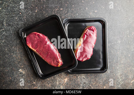 Fresh raw beef meat in foil box on old kitchen table. Stock Photo