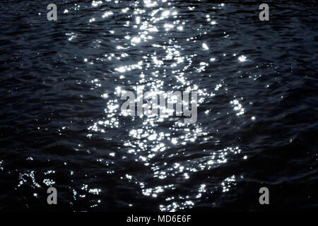 Blured sunset lights shining on the water. Stock Photo