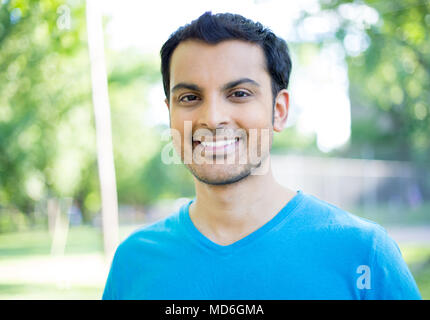Closeup headshot portrait, happy handsome business man in blue shirt, relaxing outside nature scene during sunny day, isolated on green trees backgrou Stock Photo