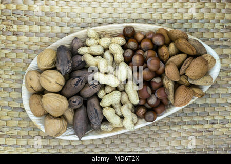 Mix of the nuts. Almonds, pecans, hazelnuts, walnuts, peanuts placed in eco natural banana leaf plate on natural bamboo tat with free space Stock Photo