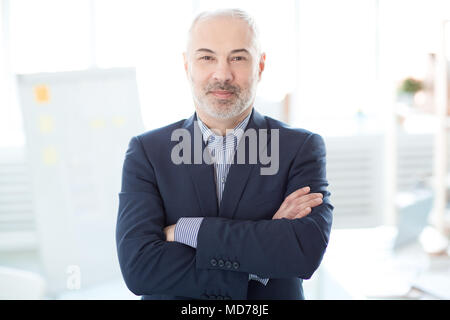 Portrait of mature businessman standing with arms crossed and looking at camera Stock Photo