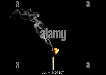 Matchstick burning with little flame and smoke on black background Stock Photo