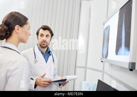 Image of two young doctors discussing x-ray results at the hospital Stock Photo