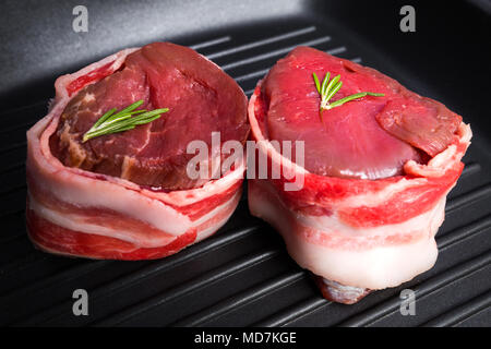 Filet mignon wrapped in fresh bacon on pan close-up. Fresh raw beef meat. Stock Photo
