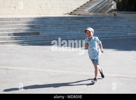 Happy little boy running on street in front of staircase, Heraklion, Greece Stock Photo