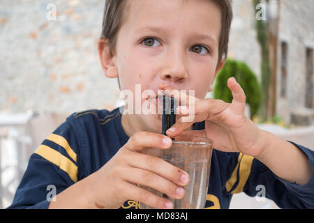 Cute little boy drinking chocolate milkshake at restaurant Stock Photo