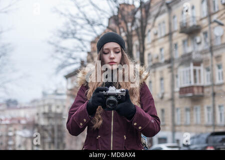 Hipster girl tourist with retro camera taking photos on city street Stock Photo