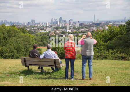 Middle-aged people relax & enjoy the panoramic view of the London skyline on a summer afternoon on Parliament Hill, Hampstead Heath, north London Stock Photo