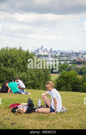 People relax and enjoy the panoramic view of the London skyline on a summer afternoon on Parliament Hill on Hampstead Heath in north London Stock Photo