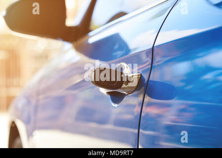 Opening modern car concept with metal key on sunny background Stock Photo