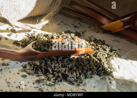 Chinese oolong  tea. Heap of tea leaves on textured linen tablecloth with bamboo spoon. Aromatic and healthy drink widely used in the world. Stock Photo