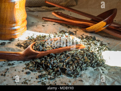 Chinese oolong  tea. Heap of tea leaves on textured linen tablecloth with bamboo spoon. Aromatic and healthy drink widely used in the world. Stock Photo