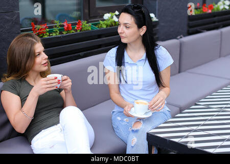 Female friends laughing and talking at cafe. Stock Photo