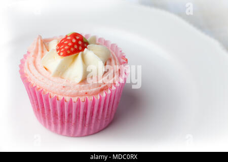Pink strawberry cupcake on white plate Stock Photo
