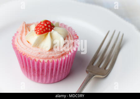 Pink strawberry cupcake on white plate with fork Stock Photo
