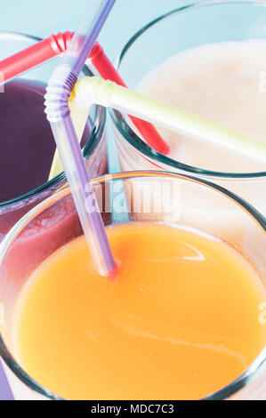 Close up of three different fruit smoothie flavours, grouped together in glasses with straws. FIltered for retro effect. Stock Photo