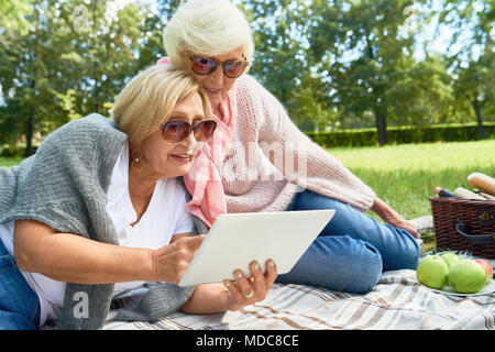 Two Senior Women Using  Tablet in Park Stock Photo