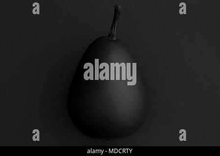 Pear Painted Black on Dark Surface Stock Photo
