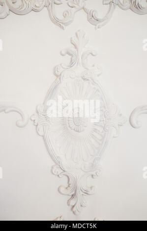 The bas-relief on a white wall.On the wall a ray of light falls. Old light interior Stock Photo