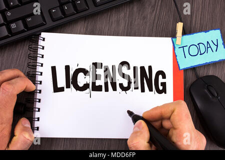 Handwriting text Licensing. Concept meaning Grant a license Legally permit the use of something Allow activity written by Man Notepad wooden backgroun Stock Photo