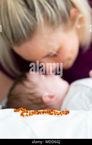 beautiful blond mother with her 3 month old baby wearing a amber necklace Stock Photo