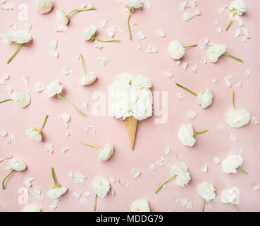 Flat-lay of waffle sweet cone with white buttercup flowers over light pink background, top view, horizontal composition. Spring or summer mood concept Stock Photo