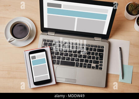 Responsive design concept on laptop and smartphone screen over wooden table. All screen content is designed by me. Flat lay Stock Photo