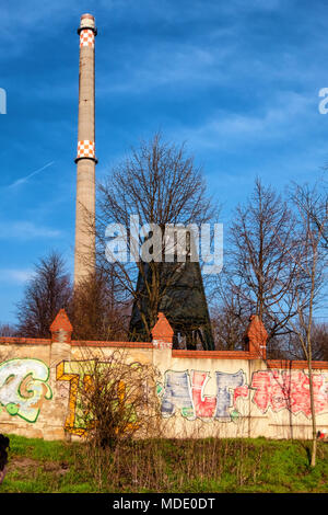 Berlin Mitte. Graffitti covered wall of Invaliden Cemetery, old industrial chimney and blue sky Stock Photo