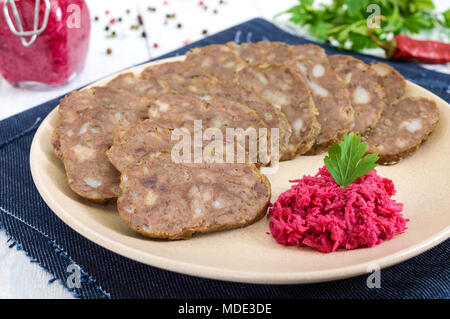 Home made dietary sausage from the liver on a white wooden table. Sausage cut into pieces on a plate with horseradish sauce. Stock Photo