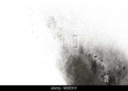 Black powder explosion against white background.The particles of charcoal splattered on white background. Closeup of black dust particles explode isol Stock Photo