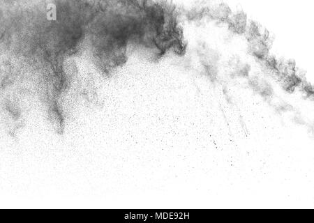 Black powder explosion against white background.The particles of charcoal splattered on white background. Closeup of black dust particles explode isol Stock Photo