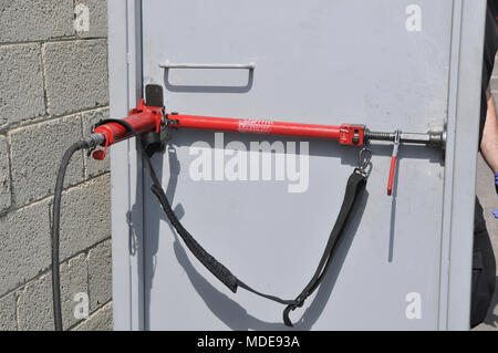 Fire fighter uses hydraulic tools to breach a locked door Stock Photo