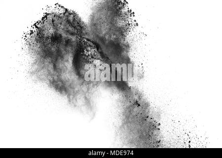Black powder explosion against white background.The particles of charcoal splattered on white background. Closeup of black dust particles explode isol Stock Photo