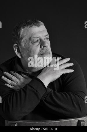 Black and white low key portrait of bearded Caucasian senior man meditating in darkness Stock Photo