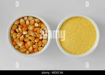 Dry corn kernels and corn flour in bowl on white background Stock Photo