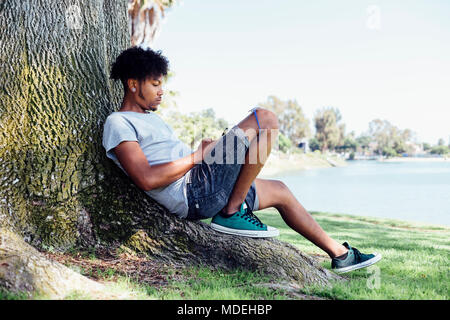 Man sitting on root of tree Stock Photo
