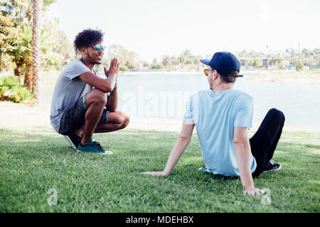 Friends relaxing on grass by lake, Long Beach, California, US Stock Photo