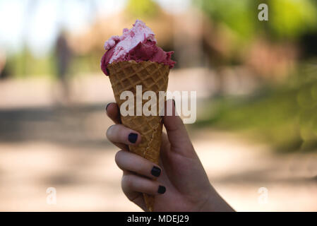 Woman's hands holding melting ice cream waffle cone in hands on summer light nature background Stock Photo