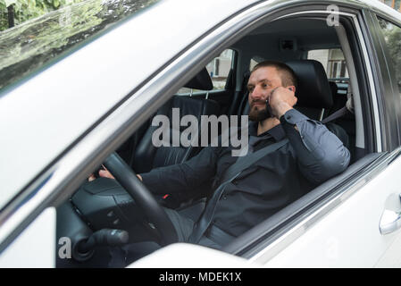 Bearded man talking on the phone while driving Stock Photo