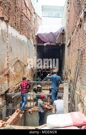 Vietnamese workmen on a small construction site laying bricks a doing formwork for the basement of a building in Ho Chi Minh City, Vietnam. Stock Photo