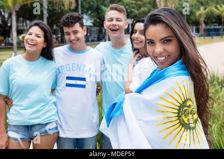 Beautiful argentinian sports fan with other supporters from Argentina outdoors on way to stadium Stock Photo